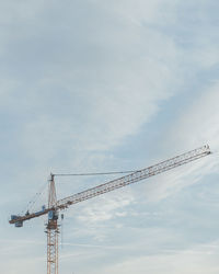 Low angle view of cranes at construction site against sky