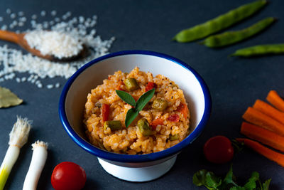 Italian vegan spring risotto on black dish with asparagus on dark dish with colorful pepper parsley