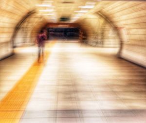 Blurred motion of people walking in illuminated tunnel