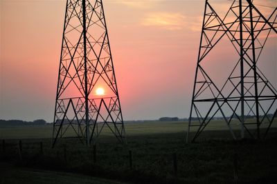 Silhouette electricity pylon on field against sky during sunset