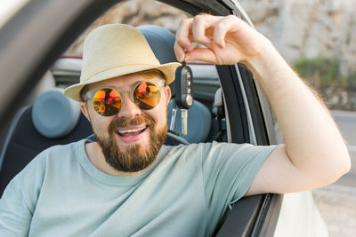 Portrait of young man wearing sunglasses while sitting in car