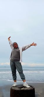 Full length of carefree woman standing at beach