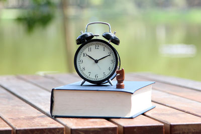 Close-up of clock with book and knight on table