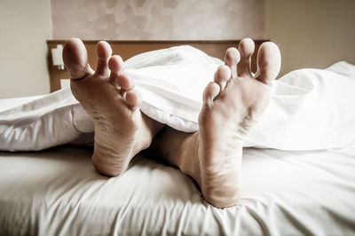 Low section of man resting on bed