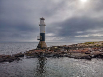 Lighthouse by sea against sky