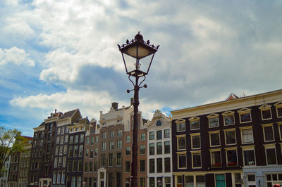 Low angle view of street light by building against sky