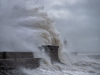 Waves splashing on shore against sky