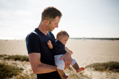 Father cradling infant son on beach