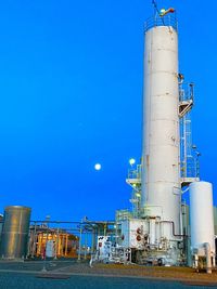 Low angle view of factory against clear blue sky