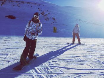 People snowboarding on field during winter