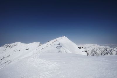 Scenic view of snowcapped mountains against clear blue sky