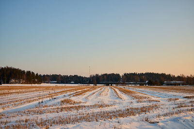 Snow covered field against clear sky during winter