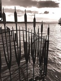 Wooden posts on beach against sky during sunset