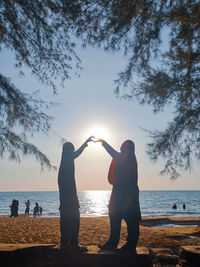 People standing at beach against sky