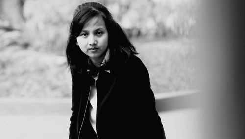 Portrait of woman standing against blurred background