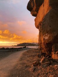 Rock formation on beach against sky during sunset