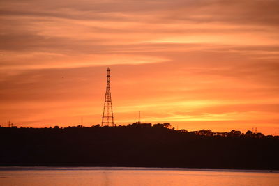 Silhouette electricity pylon against romantic sky at sunset