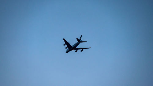 Low angle view of airplane flying against clear blue sky