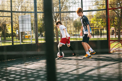 Two teenagers play freestyle soccer on a special playground. boys run after the ball. sport