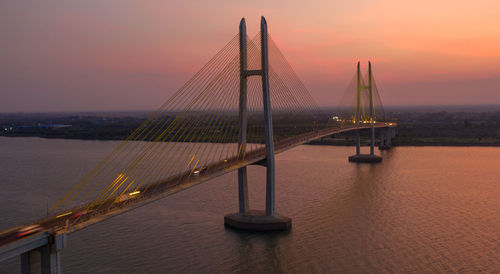 View of suspension bridge over sea during sunset