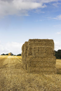 Hay bales on field against sky