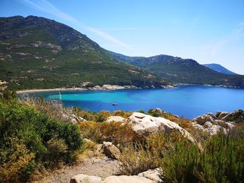 Scenic view of lake and mountains against blue sky