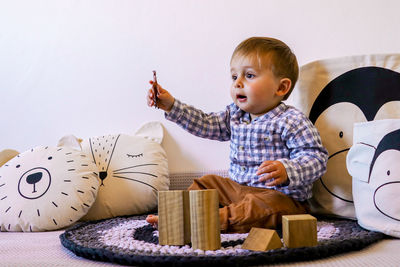 Cute boy looking away while sitting on toy at home