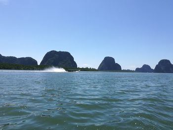 Scenic view of sea and rocks against clear blue sky