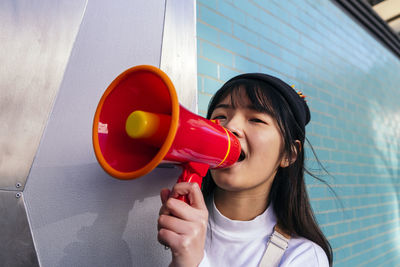 Woman shouting through megaphone from behind door