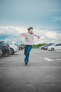 Full length of man running on road in city against sky