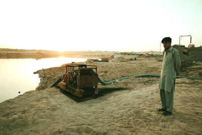 Rear view of man standing on beach against clear sky