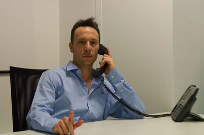 Portrait of businessman talking on telephone while sitting at office