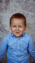 Portrait of boy standing against wall