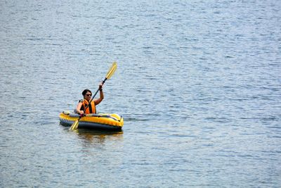 Woman rowing while sitting in boat on sea