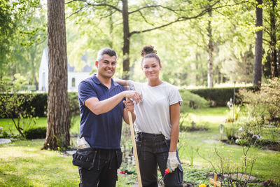 Portrait of smiling female trainee standing with hand on instructor's shoulder at garden