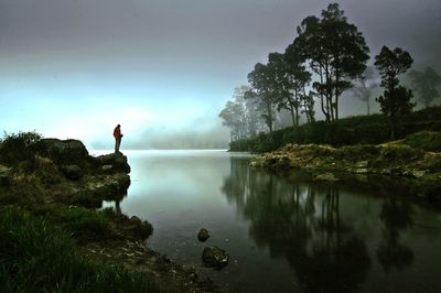 Rear view of man on lake against sky