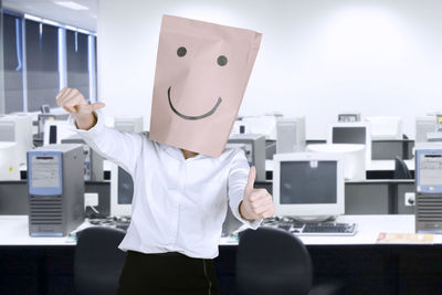 Businesswoman wearing paper bag with anthropomorphic face in office