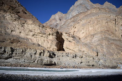 Low angle view of rocky mountains by river