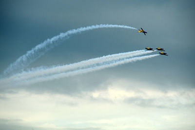 Low angle view of airshow in cloudy sky