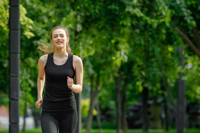 Portrait of smiling woman jogging at park