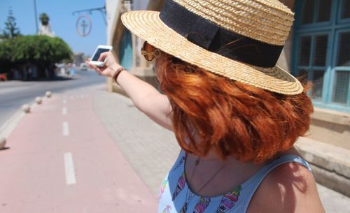 Rear view of woman using mobile phone in city