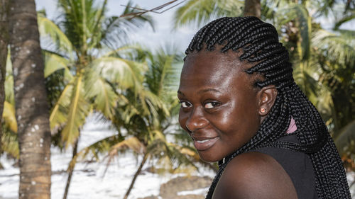 Portrait of smiling young woman against trees