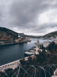 High angle view of city by river and buildings against sky