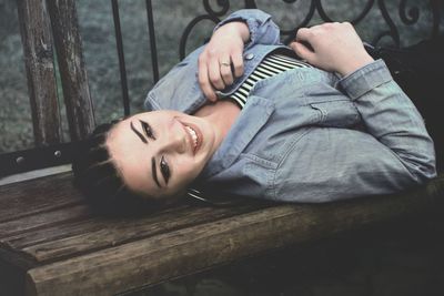 Portrait of smiling young woman lying on bench