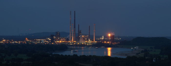 Illuminated factory against sky at night