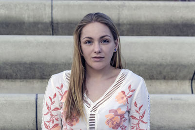 Portrait of beautiful young woman standing against wall