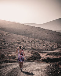 Rear view of woman walking on dirt road