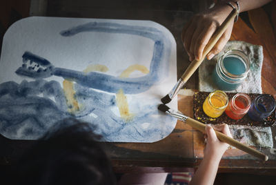 Directly above shot of girl painting on paper