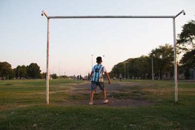 Rear view of boy on field against sky