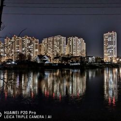 River by illuminated buildings against sky at night